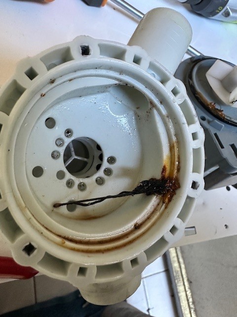 An Encore Service technician working on a washing-machine drain pump.